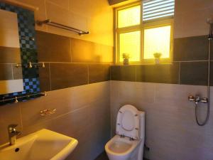 een badkamer met een toilet, een wastafel en een raam bij DAZZLET RWANDA in Kigali