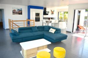 uma sala de estar com um sofá azul e bancos amarelos em Villa neuve sur pilotis vue mer à 30m de la plage em Plérin