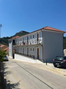 un grande edificio bianco con un'auto parcheggiata di fronte di Vassilis Retreat ad Ásos