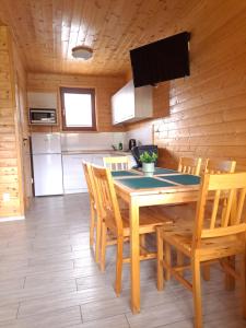 a kitchen with a wooden table and chairs in a room at Tropikana Domki, Apartamenty in Mielno