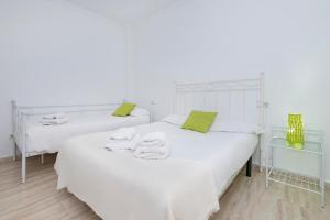 - 2 lits dans une chambre blanche avec des touches de vert dans l'établissement Fuengirola Sensaciones de Verano, à Fuengirola