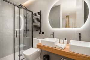 Un baño con lavabo, inodoro y espejo. en Gran Via VII 2BR 2BH, en Madrid 45 fotos más