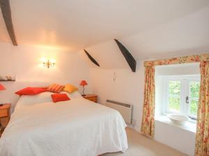a bedroom with a white bed and a window at Milton Cottage, Nr Thurlestone - a delightful thatched cottage close to the beach in Thurlestone