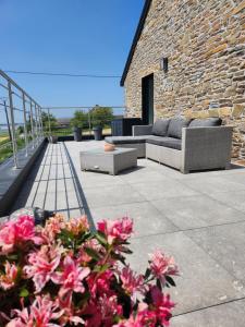 eine Terrasse mit Sofas und Blumen vor einem Steingebäude in der Unterkunft Le panorama in Dinant