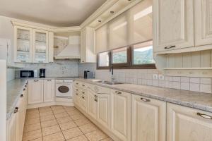 uma cozinha com armários brancos e um lavatório em Ananta Blue Residence em Argasi