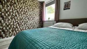 a bedroom with a bed with a green blanket and a window at Apartamenty Karkonoska Polana in Staniszów