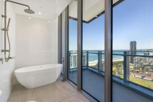 a bathroom with a white tub and large glass windows at ULTIQA Signature at Broadbeach in Gold Coast