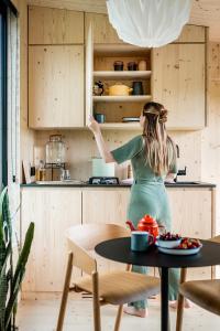 a woman reaching into the cabinets of a kitchen at Slow Cabins Kinvara in Kinvara