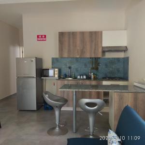 a kitchen with a table and two stools and a refrigerator at APPARTMENT( LA PAPAYA) in La Gaulette