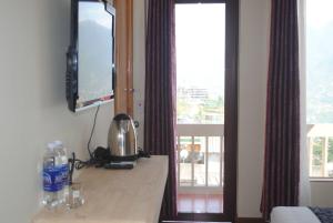 サパにあるボタニック サパ ホテルの窓のあるカウンターとテレビが備わる客室です。