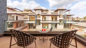 Villa Amara 29 by Stay ALYF, Lonavala في لونافالا: بلكونه فيها كرسيين وطاولة ومبنى