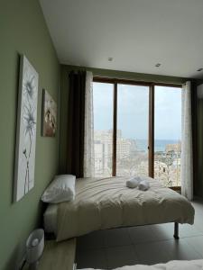 ein Schlafzimmer mit einem Bett und einem großen Fenster in der Unterkunft Entire Luxury Sliema Townhouse Steps from Beach in Sliema