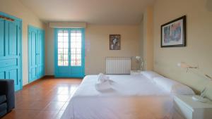 a bedroom with a large white bed and a blue door at Resort Camping Santillana del Mar in Santillana del Mar
