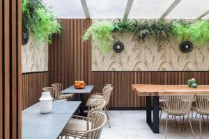 a restaurant with tables and chairs and a wall with plants at Hotel Khla Nice in Nice
