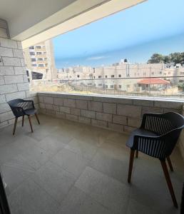 Elle comprend un balcon avec deux chaises et une grande fenêtre. dans l'établissement Dar Al Mauge Boutique Hotel with Outdoor Pool, à Bethléem