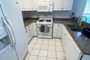 a white kitchen with a stove and a sink at Bay Motel in North Bay