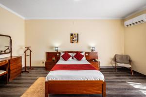 a bedroom with a bed with red pillows and a desk at Hotel Colmeia in Monte Real