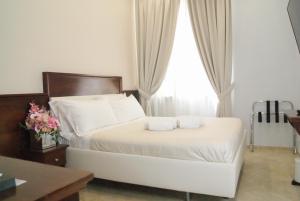 Schlafzimmer mit einem Bett mit weißer Bettwäsche und einem Fenster in der Unterkunft Esposizione Boutique in Rom