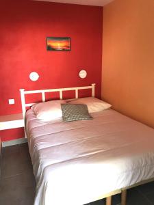 1 dormitorio con 1 cama con pared roja en Cap Estérel by Actisource, en Agay - Saint Raphael