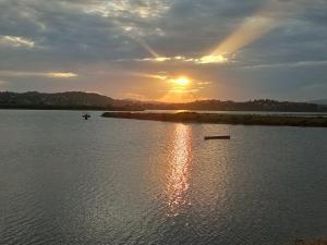 a sunset on a river with a boat in the water at La Corona d' oro in Kanoni