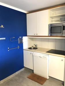 una cocina con armarios blancos y una pared azul en Cap Estérel by Actisource, en Agay - Saint Raphael