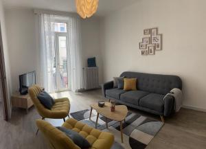 uma sala de estar com um sofá e cadeiras e uma televisão em Appartement T4 70m2 - meublé - centre ville - proche Thermes em Lons-le-Saunier