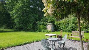 a table and chairs and a bench in a garden at L'ancienne Gendarmerie in Saint-Laurent-sur-Gorre