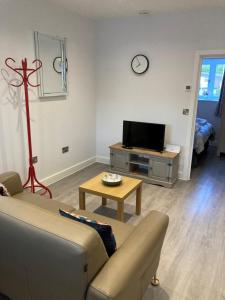 a living room with a couch and a tv and a table at Dartmoor View one bedroom Apartment Dog Friendly Close To Town FREE PARKING in Totnes