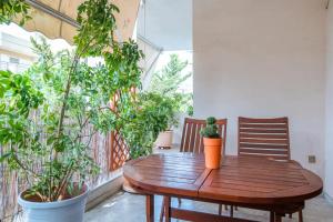 Sunny Apartment في أثينا: طاولة خشبية على شرفة مع نباتات الفخار