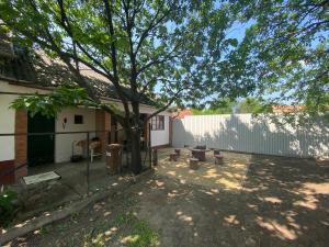 a backyard with a tree and a fence at Emese Vendégház in Tiszafüred