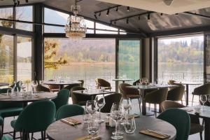 un restaurant avec des tables et des chaises et une grande fenêtre dans l'établissement La Villa du Lac, à Aiguebelette-le-Lac