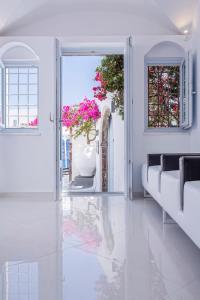 an open door into a room with white walls and flowers at Canaves Ena - Small Luxury Hotels of the World in Oia