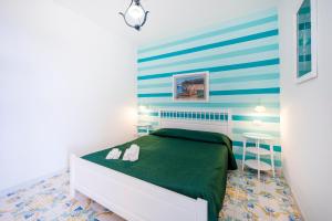 a bedroom with a green bed and a striped wall at Marina del Cantone Chalet in Nerano
