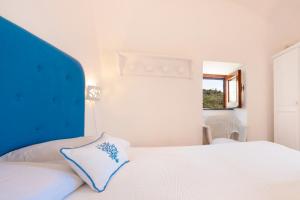 a bedroom with a white bed with a blue headboard at Marina del Cantone Chalet in Nerano