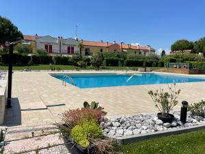 ein großer Swimmingpool in einem Hof mit Felsen und Pflanzen in der Unterkunft LunaSole Casa vacanza mare in Aprilia Marittima
