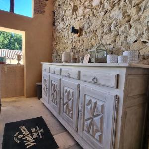 een witte dressoir in een kamer met een stenen muur bij Maison avec grange & piscine vue sur les Pyrénées in Puymaurin