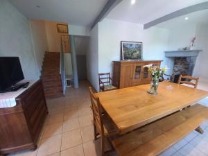 una sala da pranzo con tavolo in legno e TV di Maison avec jardin ad Adé