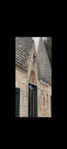 um pequeno edifício de pedra com uma janela com persianas verdes em I Trulletti di nonna MIMMA em La Correggia
