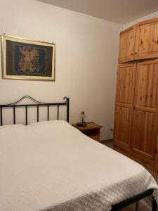 um quarto com uma cama branca e um armário de madeira em I Trulletti di nonna MIMMA em La Correggia