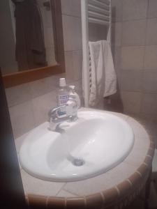 um lavatório branco com uma garrafa de sabão em I Trulletti di nonna MIMMA em La Correggia