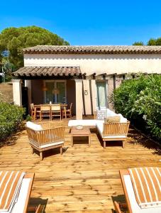 una terraza de madera con bancos, una mesa y una casa en Window On Ramatuelle en Saint-Tropez