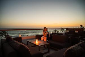 a woman sitting on a couch watching the sunset at Riff Hikkaduwa in Hikkaduwa