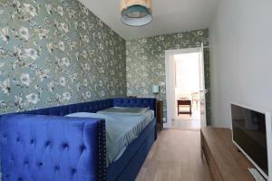 a blue bed in a bedroom with floral wallpaper at Le Gentiane - Villa Chanterive in La Bourboule