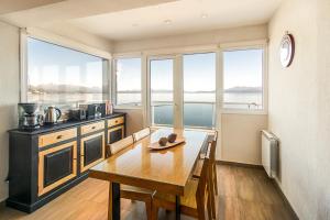 Una cocina con una mesa con sillas y ventanas. en Bariloche costa del lago Ollagua, vista al lago panoramica, piscina, cochera, en San Carlos de Bariloche