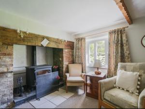 a living room with a fireplace and a chair at Millwater Cottage in Axminster