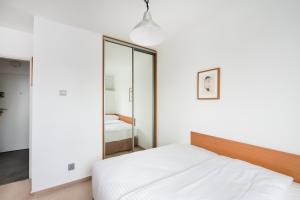 a white bedroom with a bed and a mirror at Metro Rondo ONZ Yellow Apartment in Warsaw
