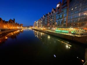 een rivier in een stad 's nachts met gebouwen bij Sun&Sand11 in Gdańsk