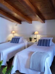 two beds in a room with white walls and wooden ceilings at Hostal de la Plaça - Hotel Boutique in Cabrils