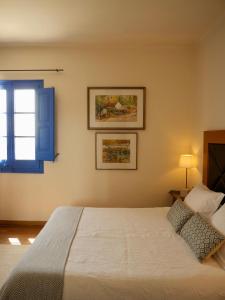 a bedroom with a white bed with a blue window at Hostal de la Plaça - Hotel Boutique in Cabrils