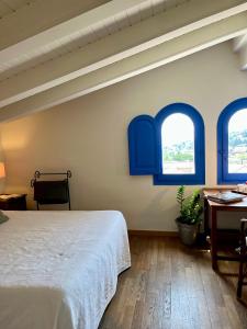 a bedroom with blue windows and a bed at Hostal de la Plaça - Hotel Boutique in Cabrils